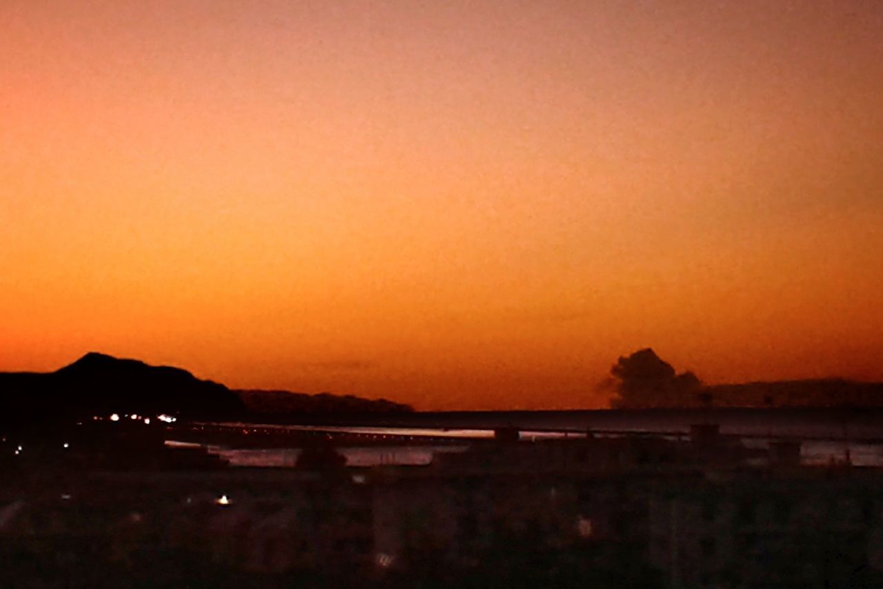 SILHOUETTE MOUNTAINS AGAINST ORANGE SKY