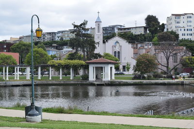 Lamppost by lake merritt against buildings in city