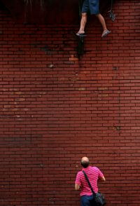 Rear view of man looking at person standing against wall