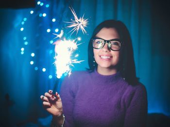 Smiling young woman with illuminated firework at night