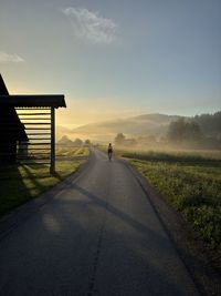 Scenic view of a cyclist on a field against sky during sunrise