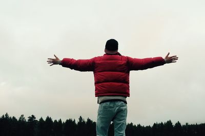 Rear view of man with arms outstretched against sky