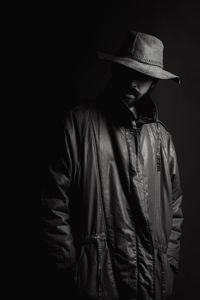 Man wearing hat standing against black background