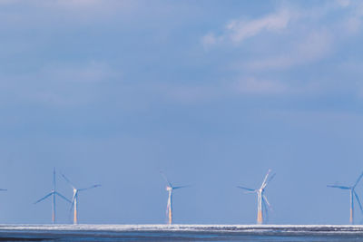 Wind turbines on beach against sky