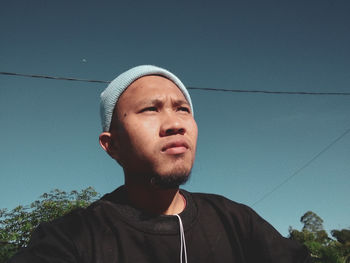 Portrait of young man looking away against sky