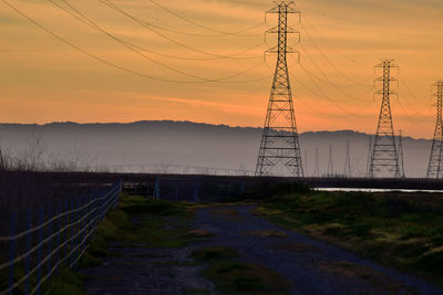 Electricity pylon on field against sky during sunset