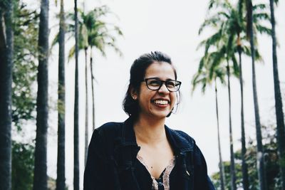 Portrait of smiling young woman against trees