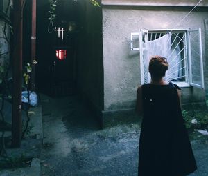 Rear view of woman standing by window at night