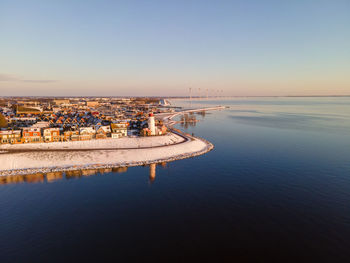 Aerial view of sea and buildings against sky during sunset