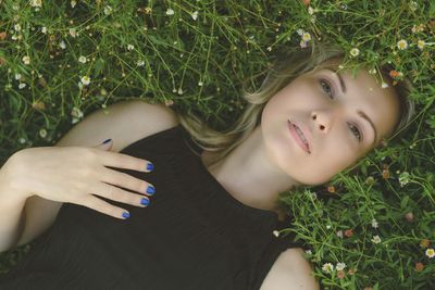 High angle portrait of woman lying on grassy field in park