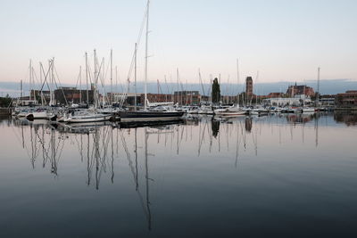 Sailboats in marina at harbor against clear sky