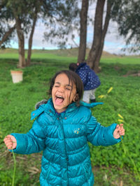 Happy girl with arms raised on field