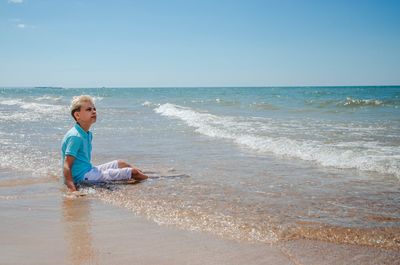 Rear view of woman standing at beach against sky