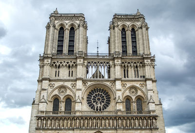 Low angel view of notre dame de paris against cloudy sky