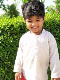 Close-up of smiling boy standing against plants