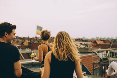 Rear view of friends walking on terrace during rooftop party against sky