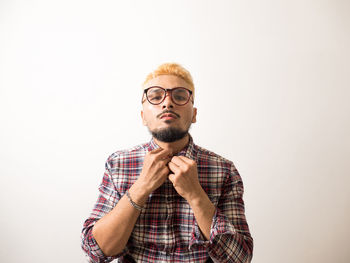 Portrait of young man standing against white background