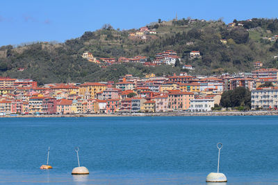 Aerial view of townscape by sea against sky