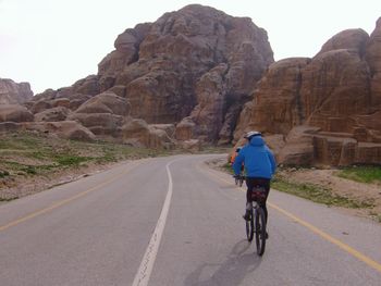 Rear view of person riding bicycle on road