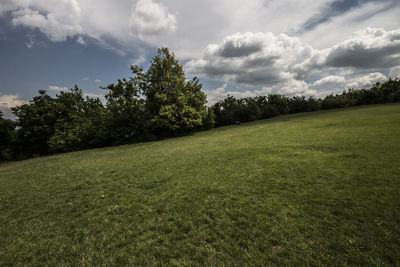 Scenic view of grassy field against cloudy sky