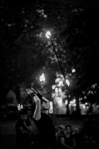 People holding illuminated lighting equipment at night