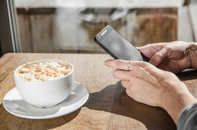 Close-up of hand with smart phone coffee