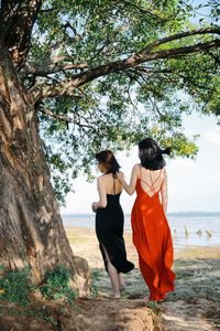 Rear view of women standing by tree