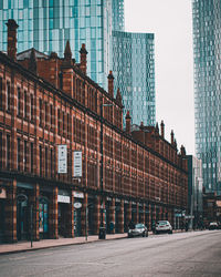 Street by buildings against sky in city