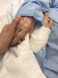 Cropped image of patient holding hand with person at hospital