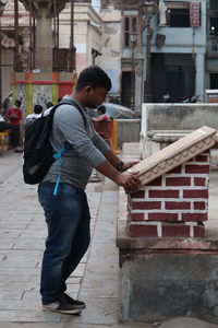Side view of teenage girl standing against building