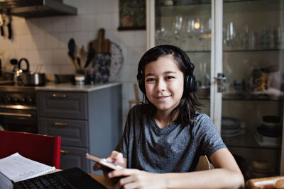 Portrait of smiling boy using mobile phone for e-learning at home