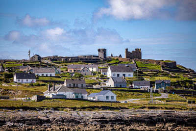 Panoramic cityscape of houses and old 15th century ruined castle against blue sky