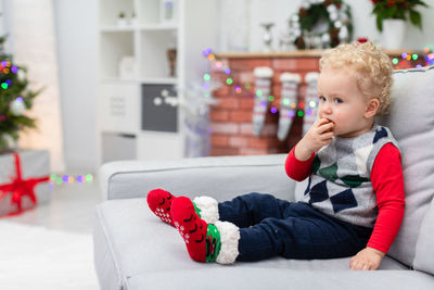 Portrait of cute baby boy sitting on bed at home