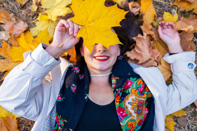 Portrait of smiling young woman holding autumn leaves