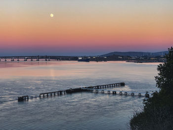 Bridge over sea against sky during sunset