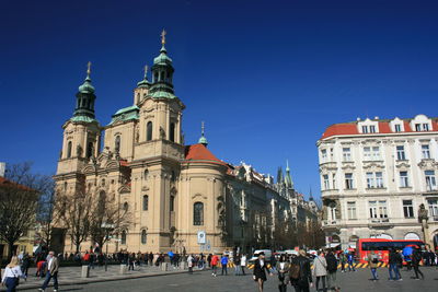 Group of people in front of building against clear blue sky