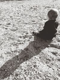 Rear view of woman sitting on sand at beach