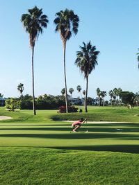 Side view of man playing golf on course against blue sky