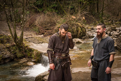 Warriors standing on riverbank in forest