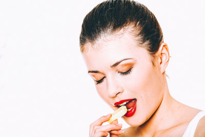 Portrait of woman holding ice cream against white background