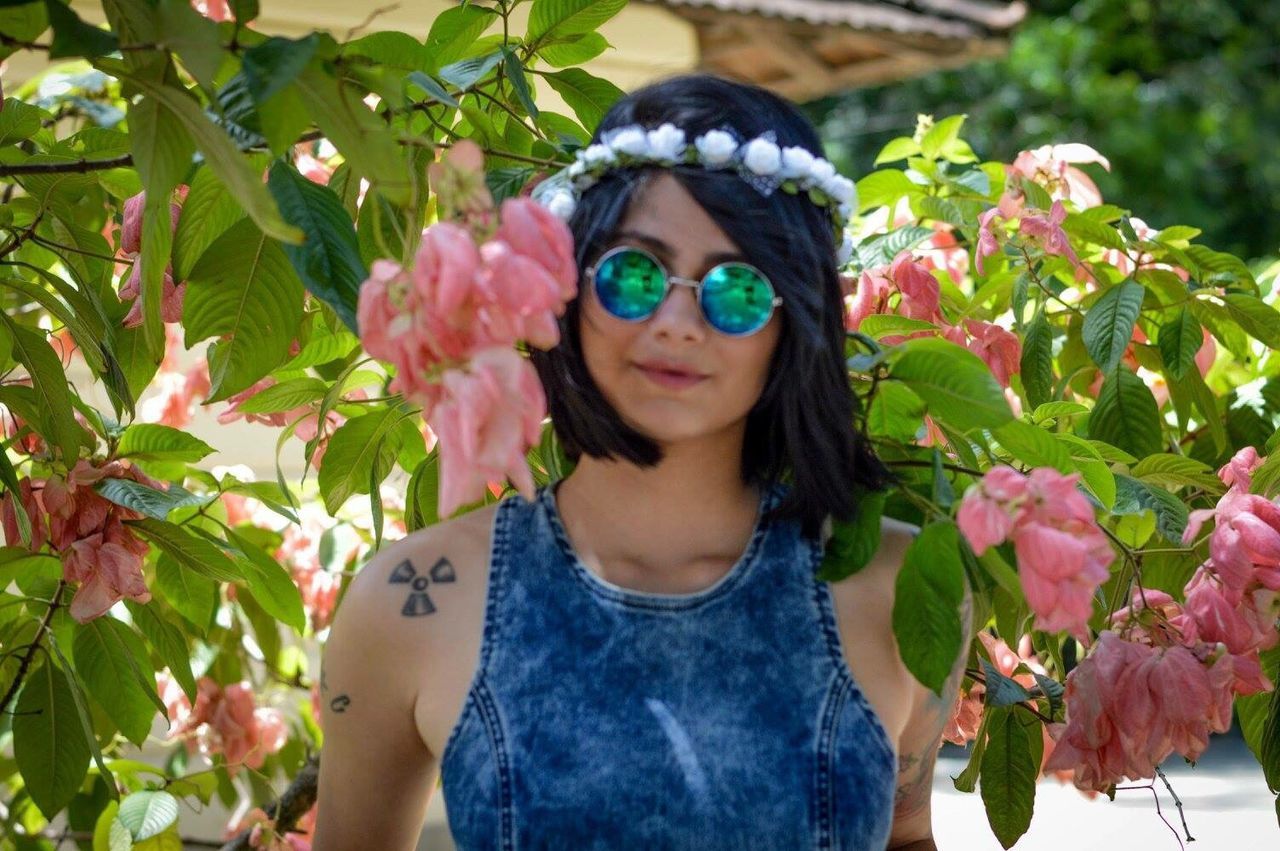 leaf, flower, young women, front view, lifestyles, leisure activity, plant, young adult, beauty, freshness, growth, person, blooming, pink color, beauty in nature, long hair, nature, day, outdoors, looking at camera, multi colored, focus on foreground