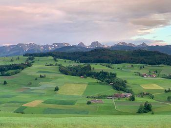 Scenic view of green landscape and mountains against sky