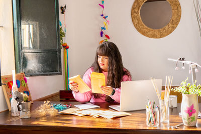 Portrait of woman using digital tablet while sitting on table