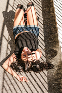 Portrait of woman lying down on road in sunny day