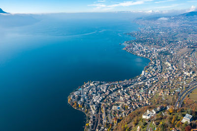 Aerial view of city by sea against sky