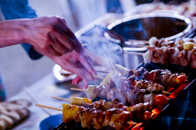 Close-up of person preparing food on barbecue grill