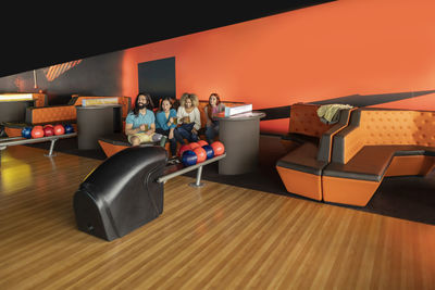 Multiracial friends sitting on sofa in bowling alley