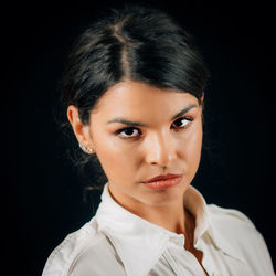 Close-up portrait of young woman against black background