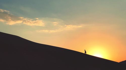 Low angle view of silhouette man walking against sky during sunset
