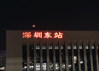 Low angle view of illuminated sign against building at night